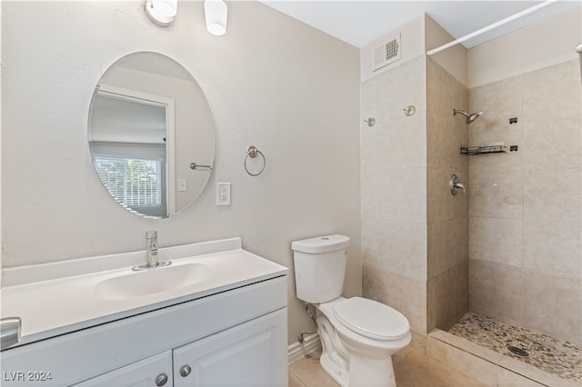 bathroom featuring tiled shower, vanity, toilet, and tile patterned flooring