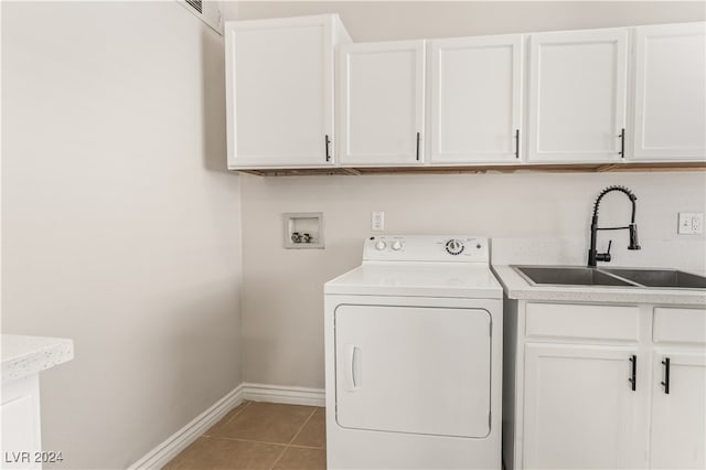 clothes washing area featuring sink, light tile patterned floors, cabinets, and washer / dryer