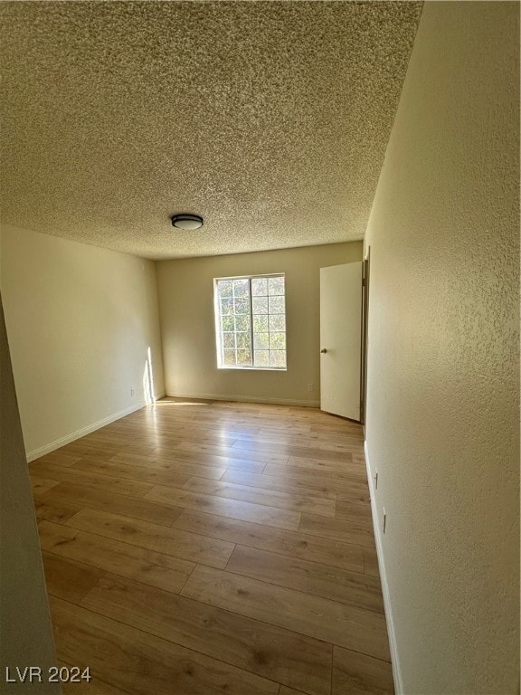 spare room with light wood-type flooring and a textured ceiling