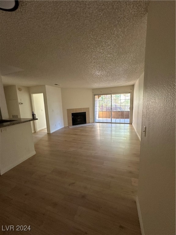 unfurnished living room featuring wood-type flooring and a textured ceiling