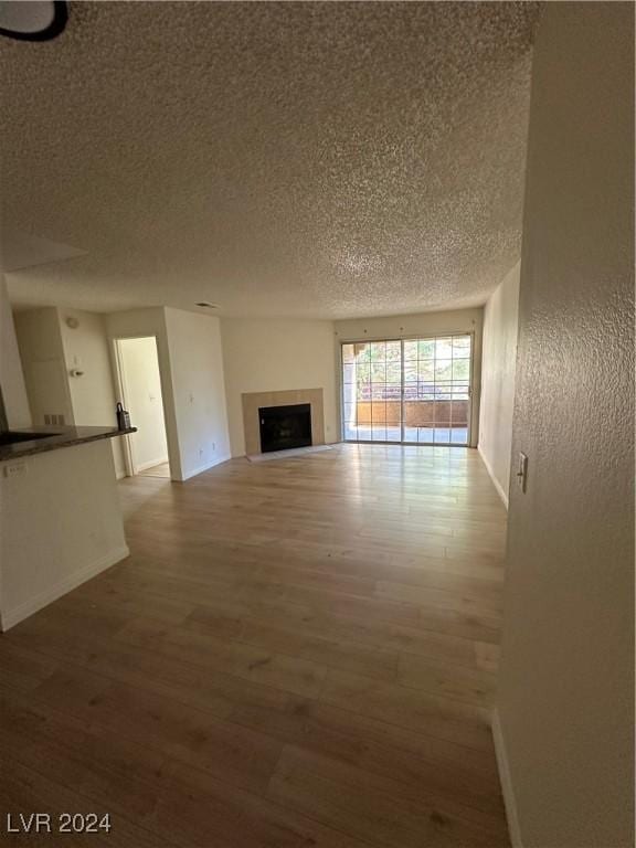 2200 S Fort Apache Rd Unit 2133, Las Vegas, NV 89117 - unfurnished living room with a textured ceiling, wood finished floors, baseboards, and a fireplace