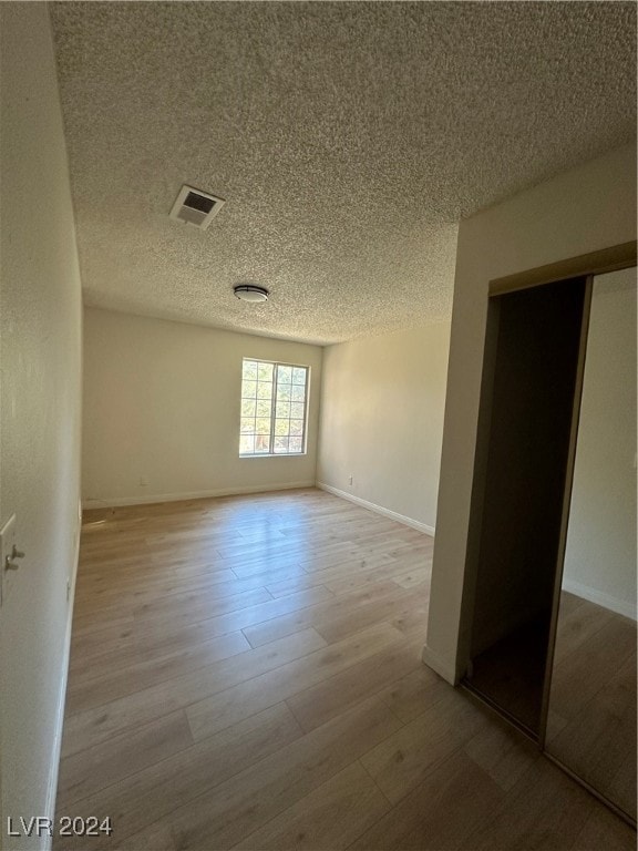 spare room with light hardwood / wood-style flooring and a textured ceiling