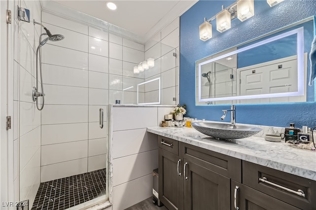 bathroom with ornamental molding, vanity, and a shower with door