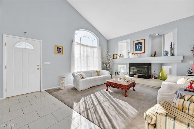 living room featuring a tiled fireplace, light carpet, and high vaulted ceiling