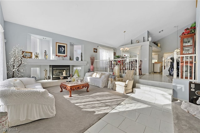 tiled living room with high vaulted ceiling, a notable chandelier, and a tile fireplace