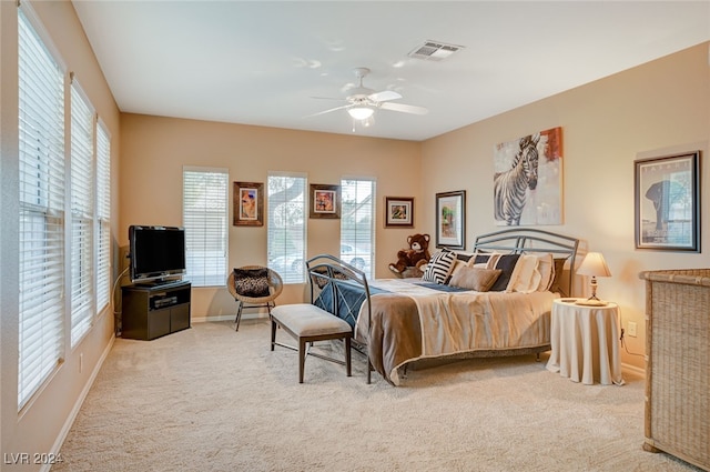 bedroom with ceiling fan, light carpet, and multiple windows