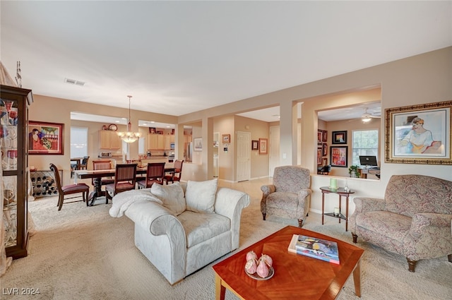 living room featuring light carpet and ceiling fan with notable chandelier