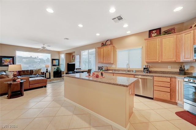 kitchen with a center island, light tile patterned floors, stainless steel appliances, and light brown cabinetry