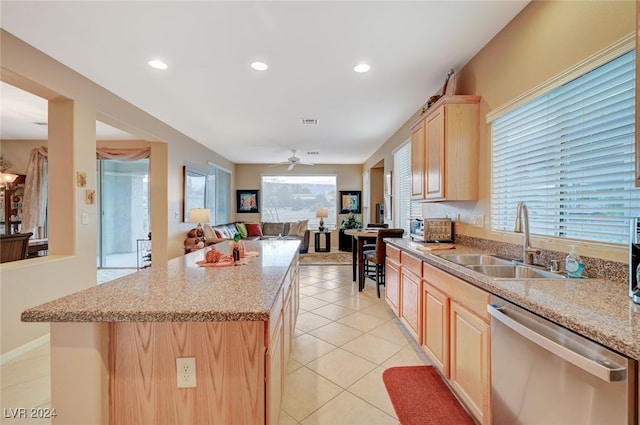 kitchen with light brown cabinetry, stainless steel dishwasher, and plenty of natural light