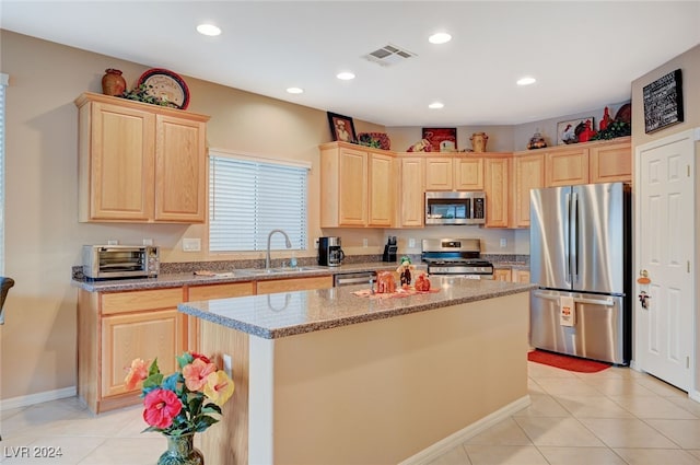 kitchen with light stone counters, stainless steel appliances, sink, a center island, and light tile patterned flooring