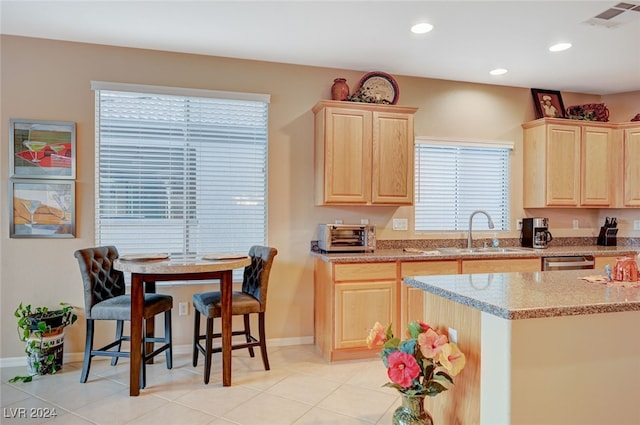 kitchen with light stone countertops, light brown cabinets, and sink