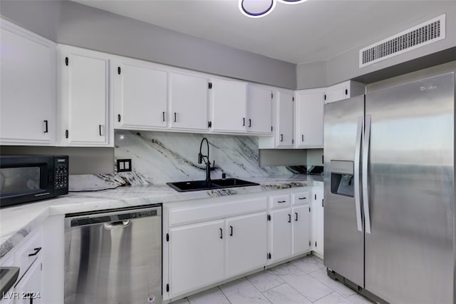 kitchen with white cabinets, sink, backsplash, and appliances with stainless steel finishes