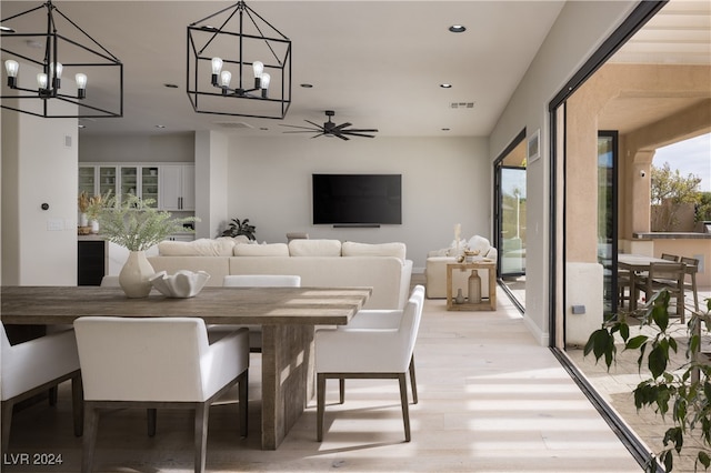 dining area featuring light hardwood / wood-style floors and ceiling fan with notable chandelier