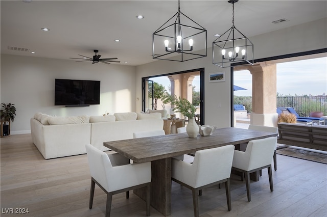 dining area with light wood-type flooring and ceiling fan with notable chandelier