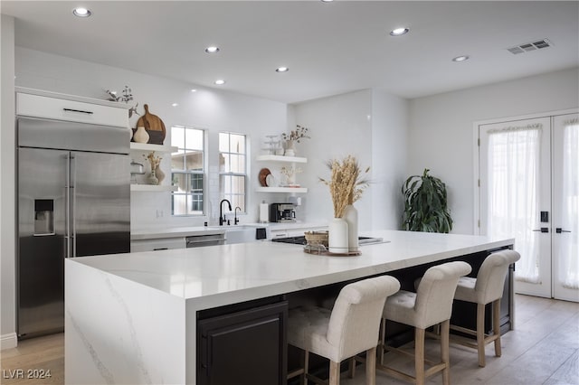 kitchen featuring stainless steel appliances, light hardwood / wood-style floors, a breakfast bar area, a kitchen island, and white cabinets