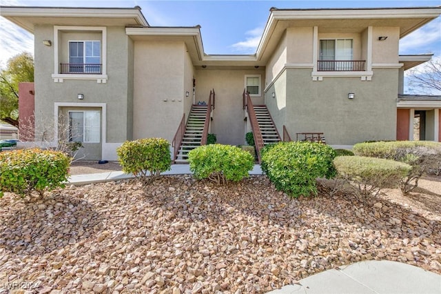 view of front of property featuring a balcony, stairway, and stucco siding