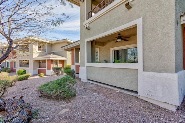 view of home's exterior featuring a balcony, a ceiling fan, and stucco siding