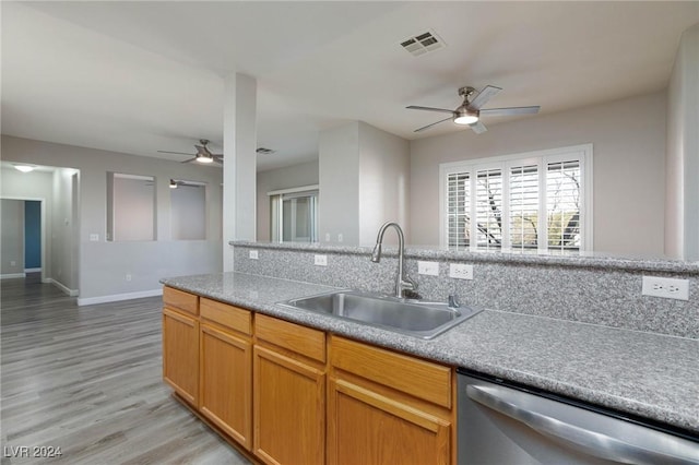 kitchen featuring light countertops, visible vents, stainless steel dishwasher, open floor plan, and a sink