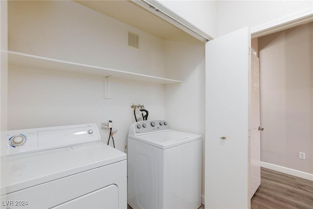 clothes washing area featuring laundry area, baseboards, visible vents, dark wood-style flooring, and washer and dryer