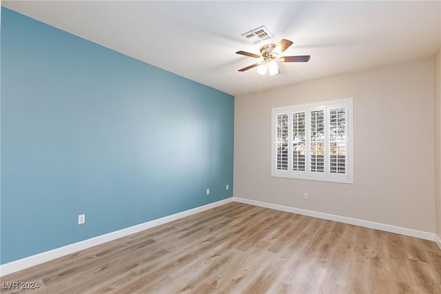 spare room featuring visible vents, ceiling fan, light wood finished floors, and baseboards