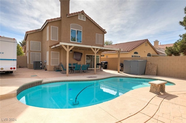 rear view of house featuring a fenced in pool, central AC unit, and a patio area