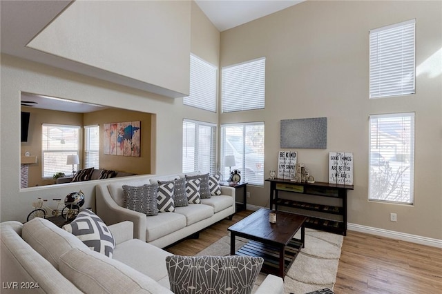 living room featuring a towering ceiling, a healthy amount of sunlight, and hardwood / wood-style flooring