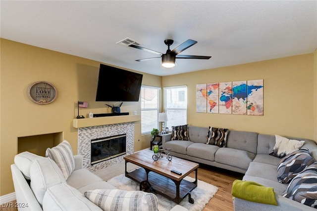 living room featuring ceiling fan, light wood-type flooring, and a fireplace