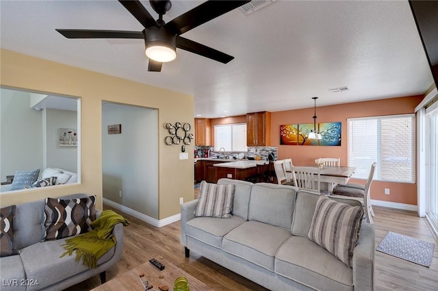 living room featuring light hardwood / wood-style flooring and ceiling fan with notable chandelier