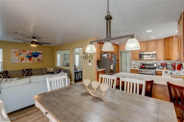 dining space with ceiling fan, sink, light hardwood / wood-style floors, and a textured ceiling