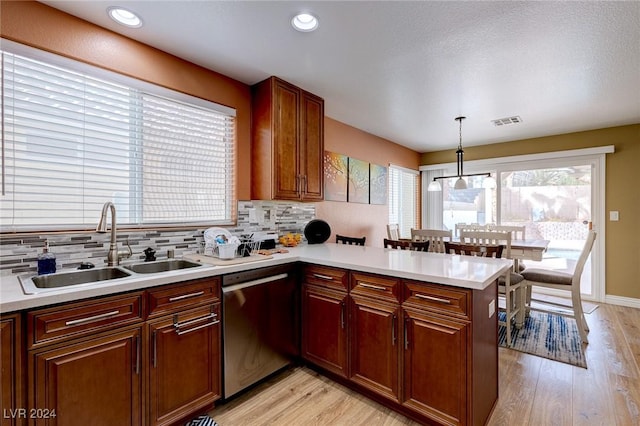 kitchen with dishwasher, sink, backsplash, kitchen peninsula, and pendant lighting