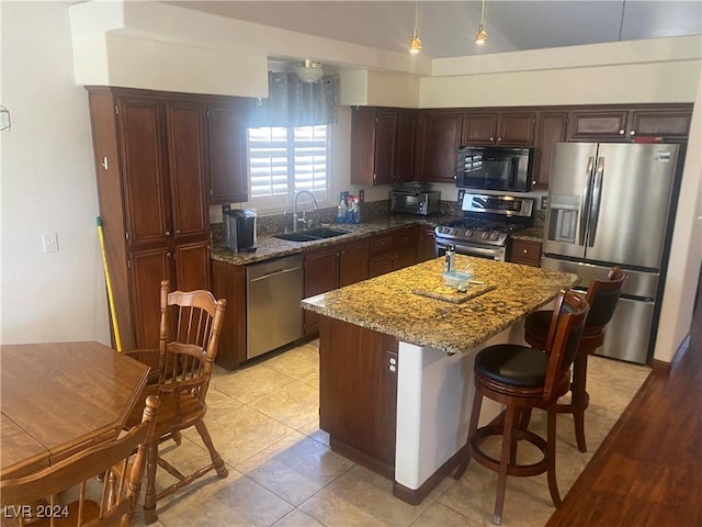 kitchen featuring sink, dark stone countertops, light tile patterned floors, a kitchen island, and appliances with stainless steel finishes