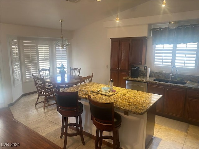 kitchen featuring sink, a kitchen island, a wealth of natural light, and dark stone counters