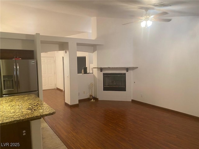 unfurnished living room featuring dark hardwood / wood-style flooring, a tile fireplace, and ceiling fan