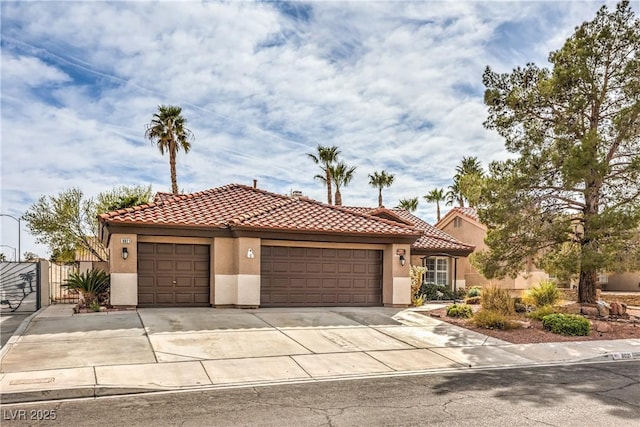 mediterranean / spanish house with a garage, driveway, a tiled roof, and stucco siding