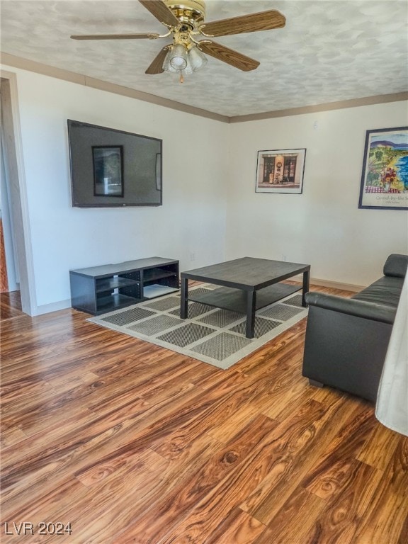 living room with hardwood / wood-style flooring, ceiling fan, and a textured ceiling