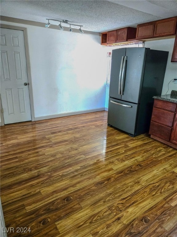 kitchen with a textured ceiling, dark hardwood / wood-style floors, and stainless steel refrigerator