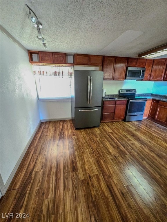 kitchen featuring track lighting, appliances with stainless steel finishes, a textured ceiling, and dark hardwood / wood-style flooring