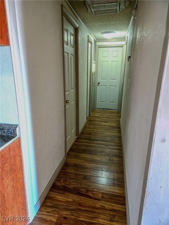 hall with dark wood-type flooring and a textured ceiling