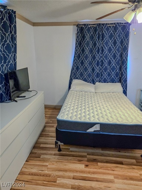 bedroom featuring hardwood / wood-style floors, ceiling fan, a textured ceiling, and ornamental molding