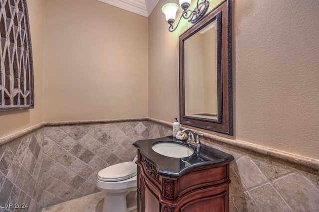 bathroom with vanity, toilet, tile walls, and ornamental molding