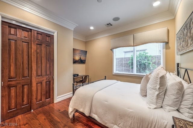 bedroom featuring crown molding, dark wood-type flooring, and a closet