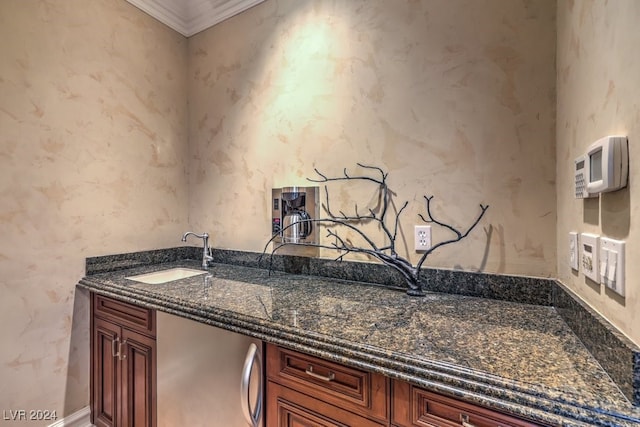 kitchen featuring sink, dark stone counters, and ornamental molding