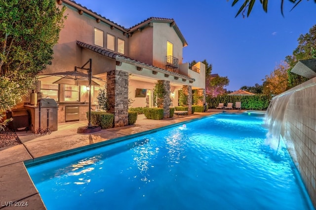 view of pool featuring pool water feature, area for grilling, and a patio area