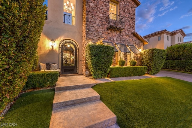 exterior entry at dusk featuring a yard