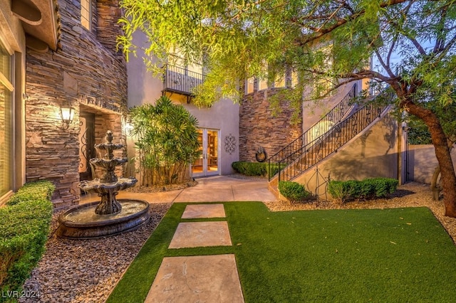 view of yard with french doors and a balcony