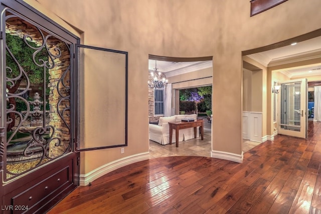 entryway with hardwood / wood-style floors, crown molding, and an inviting chandelier