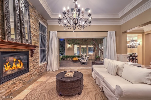 living room with a raised ceiling, a stone fireplace, a notable chandelier, and crown molding