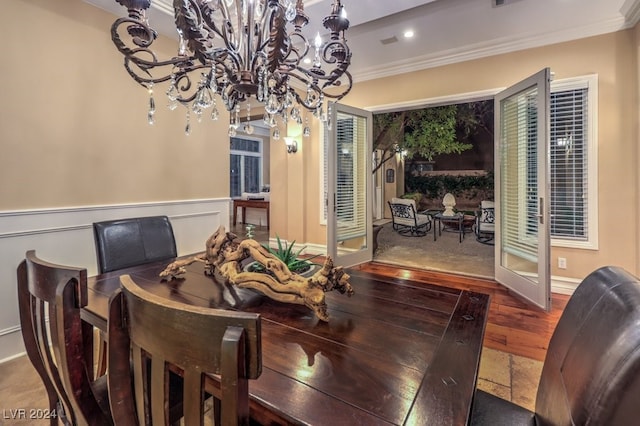 dining room with hardwood / wood-style floors, an inviting chandelier, french doors, and crown molding