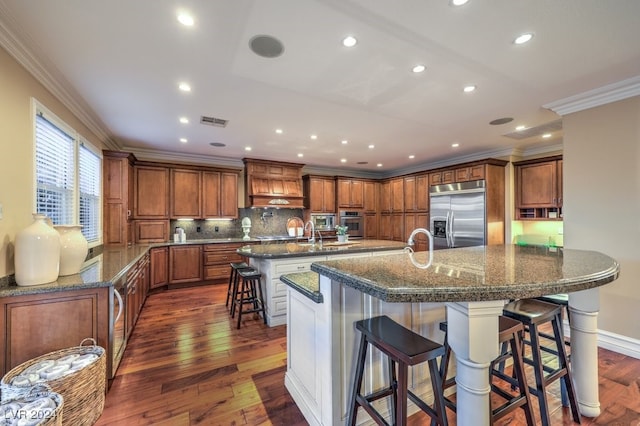 kitchen featuring a kitchen bar, decorative backsplash, stainless steel appliances, dark wood-type flooring, and a large island