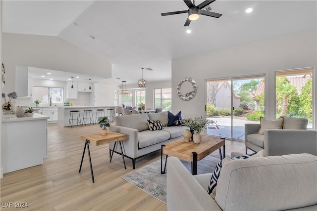 living room with ceiling fan, plenty of natural light, high vaulted ceiling, and light wood-type flooring